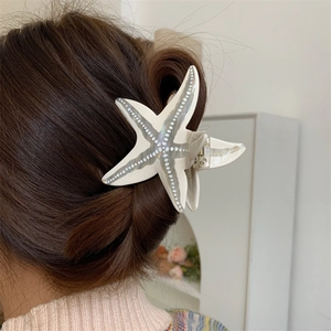 Détail arrière d'une pince à cheveux étoile de mer nacrée dans une coiffure élégante