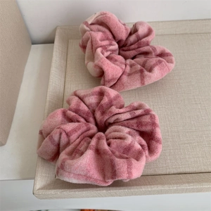 Lot de deux chouchous à carreaux roses et blancs en laine douce sur un plateau décoratif