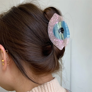 Détail d'une pince à cheveux en acétate en forme d'œil avec dégradé rose et bleu
