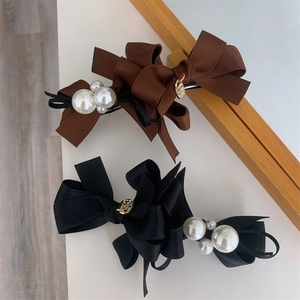 Detail view of fabric bow hair clips with white pearls and gold metal charms