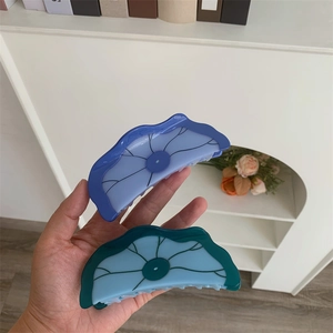 Détail des pinces à cheveux en acétate forme lotus, teintes bleu et violet élégantes