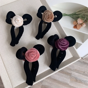 Elegant velvet flower hair claws in four colors displayed on a cream textured tray