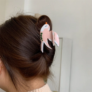 Détail d'une pince à cheveux hirondelle rose avec motifs feuilles sur cheveux bruns