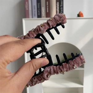 Détail d'une grande pince à cheveux en velours rose ornée de strass brillants à la main
