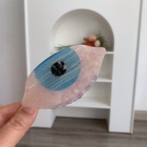 Détail de la pince à cheveux en acétate rose avec un design unique d'œil bleu