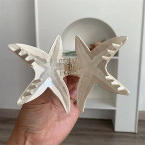 Vue détaillée de la pince à cheveux étoile de mer en acétate brillant avec ressort en métal