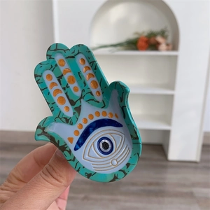 Détail de la pince à cheveux Hamsa sarcelle avec motif Evil Eye et texture acétate