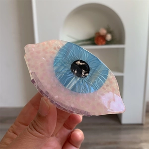 Vue macro de la pince à cheveux en acétate en forme d'œil avec iris bleu et pois roses