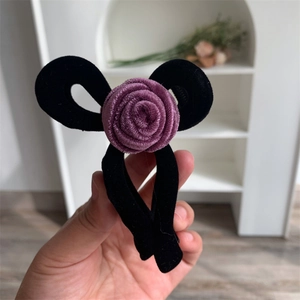 Close-up of elegant black velvet hair claw clip with a purple rose flower decoration