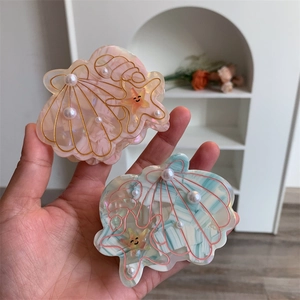Detail of seashell hair claws with marble texture pearls and a cute starfish charm