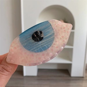 Vue détaillée d'une pince à cheveux en acétate en forme d'œil avec texture marbre rose