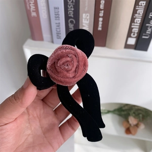 Detail of velvet flower hair claw clip with pink rose on a black fabric bow