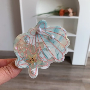 Detailed close-up of shell and starfish hair claw clip with pearls and mint green marbling