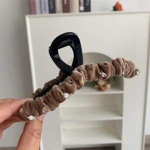 Détail d'une grande pince à cheveux en velours marron ornée de strass brillants et élégants