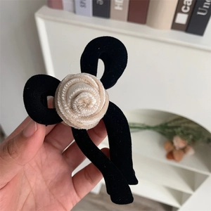 Detail view of a large velvet flower claw clip with a beige fabric rose accent