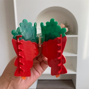 Dettaglio della molletta per capelli in acrilico rosso e verde con molla in metallo