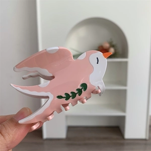 Détail d'une pince à cheveux hirondelle en acétate avec motif d'épissage rose et blanc