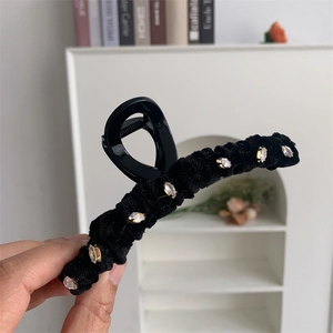 Vue détaillée de la texture en velours noir et des cristaux sur la grande pince à cheveux