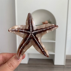 Détail d'une pince à cheveux étoile de mer en acétate avec rayures et pois blancs