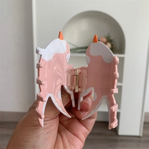 Vue détaillée de la pince à cheveux hirondelle rose et blanc avec cornes orange