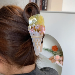 Detail view of large ice cream shaped acetate hair claw clip worn on a hair bun