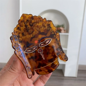Détail de la pince à cheveux tête de bouddha en acétate ambre avec sculptures fines