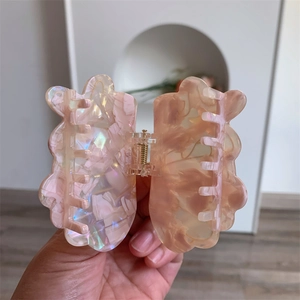 Macro detail of butterfly hair claw clip with pink marble texture and gold spring