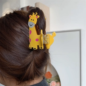 Detail view of yellow giraffe hair claw clip with pink spots on long brown hair
