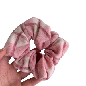 Chouchou en flanelle à carreaux roses avec motif doux présenté sur un fond blanc pur