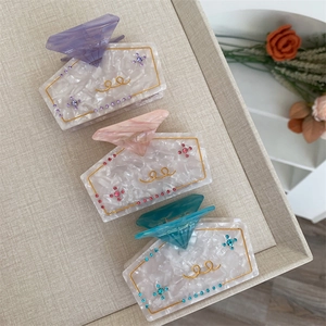 Close-up of marble texture acetate hair claws with rhinestones in lavender peach and teal