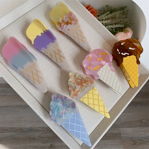 Flat lay of colorful acetate hair claws featuring realistic ice cream cone shapes on a tray