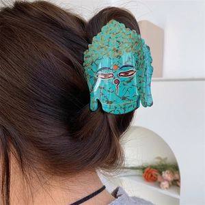 Détail de la pince à cheveux bouddha en acétate turquoise avec accents dorés sur cheveux