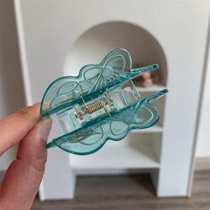 Detailed close-up of a blue butterfly hair claw clip featuring a strong gold metal spring