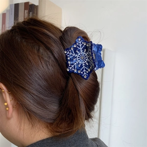 Détail d'une pince à cheveux flocon bleu foncé avec strass portée sur cheveux bruns