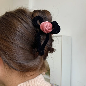 Elegant black velvet claw clip with pink rose worn on long hair for a vintage look