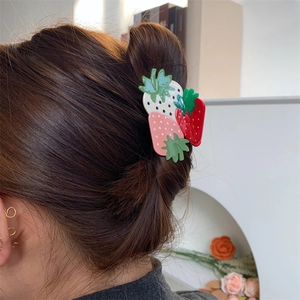Detailed side view of a model wearing a green and pink strawberry hair claw clip