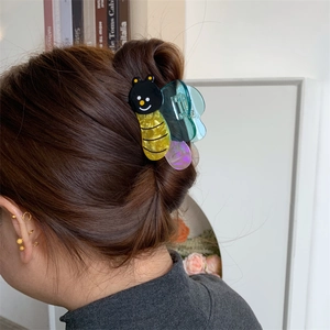 Detail of cute bear-bee acetate hair claw clip worn on hair with colorful wings