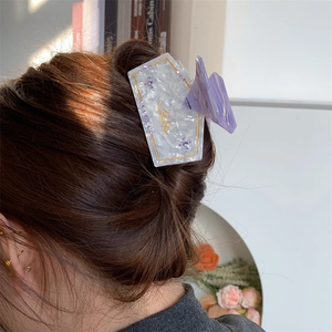 Detail view of large marble acetate hair claw with purple crystal flowers on brown hair