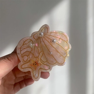 Macro view of shell and starfish hair claw clip with pink pearls and gold accents