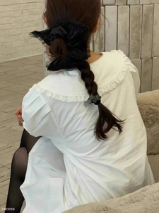 Detail of elegant black satin scrunchie with lace edge worn on a ponytail