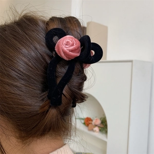 Close-up of a large black velvet bow hair claw clip with a pink flocking rose detail