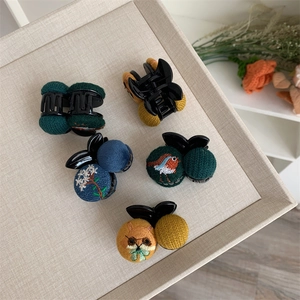 Mini hair clips featuring embroidered nature motifs like birds and flowers on fabric