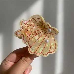 Close-up of cream acetate hair claw with shell, starfish and pearl ocean motifs