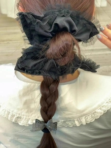 Detail of elegant black lace and satin scrunchie styled on a braided hairstyle