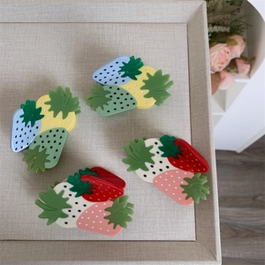 Detail of four colorful strawberry hair claws made of glossy resin in various pastel tones