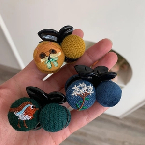 Three handmade embroidered hair clips featuring squirrel, floral, and bird patterns