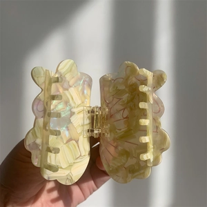 Macro detail of acetate seashell hair claw clip with golden spring in natural sunlight