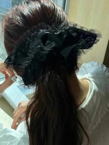 Macro view of oversized black lace scrunchie with sheer organza ruffles on ponytail