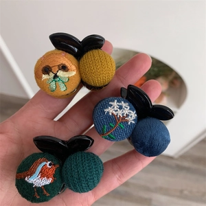 Detail showing handmade embroidered small hair clips with animal and floral patterns
