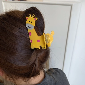 Detailed view of yellow giraffe hair claw clip with pink spots on hair bun